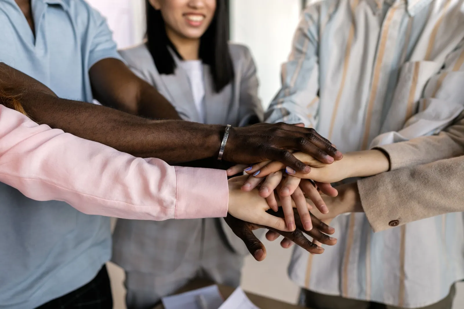 A diverse group of colleagues stack their hands together in a show of unity.