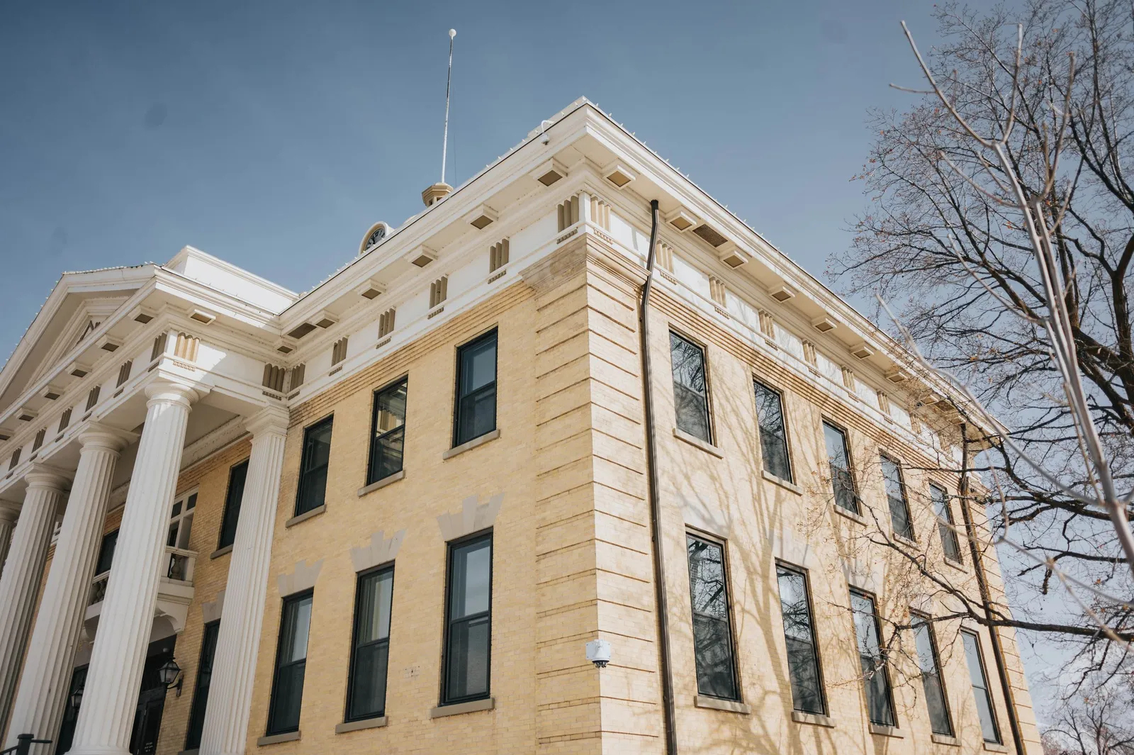 A historic courthouse with white columns stands under a clear blue sky.